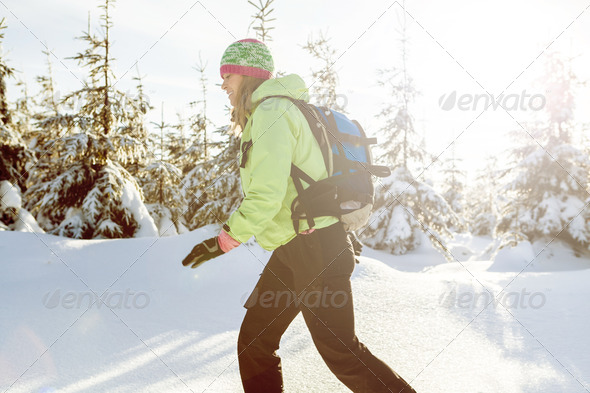 Woman hiking and walking on snow in winter mountains, sunset, Poland