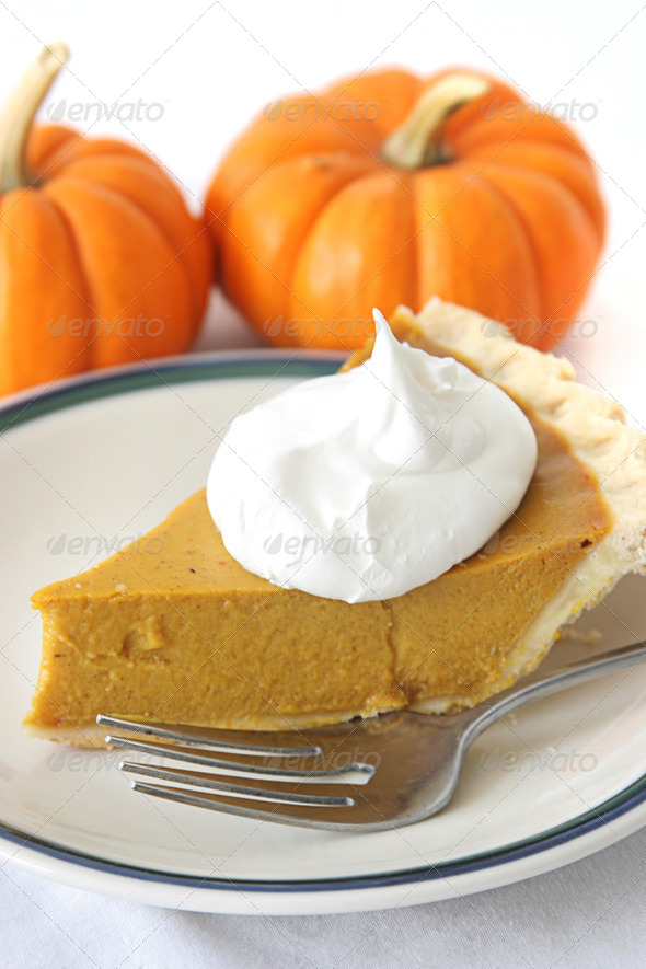 Slice of delicious holiday pumpkin pie garnished with a dollop of whipped cream.