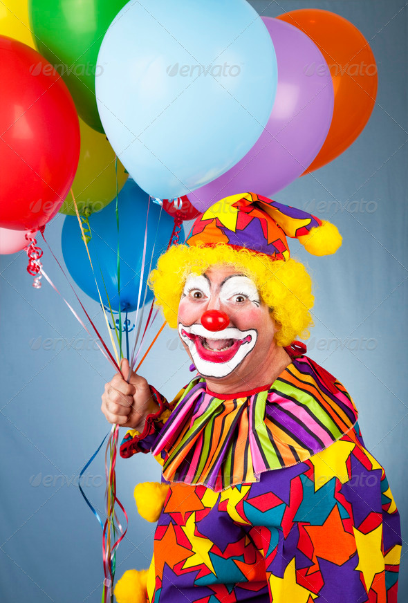 Happy clown with balloons in front of a blue background.