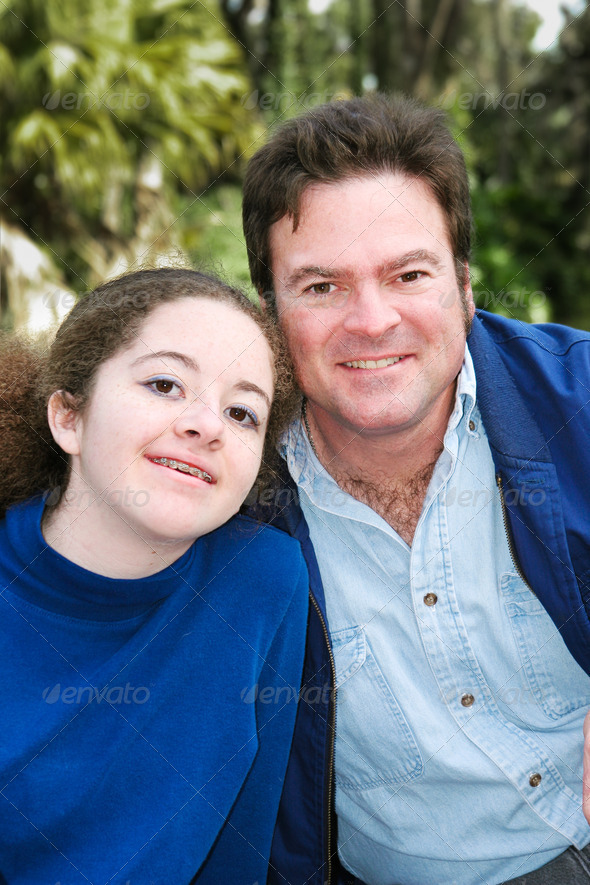 Portrait of a father and his teenage daughter posing outdoors.