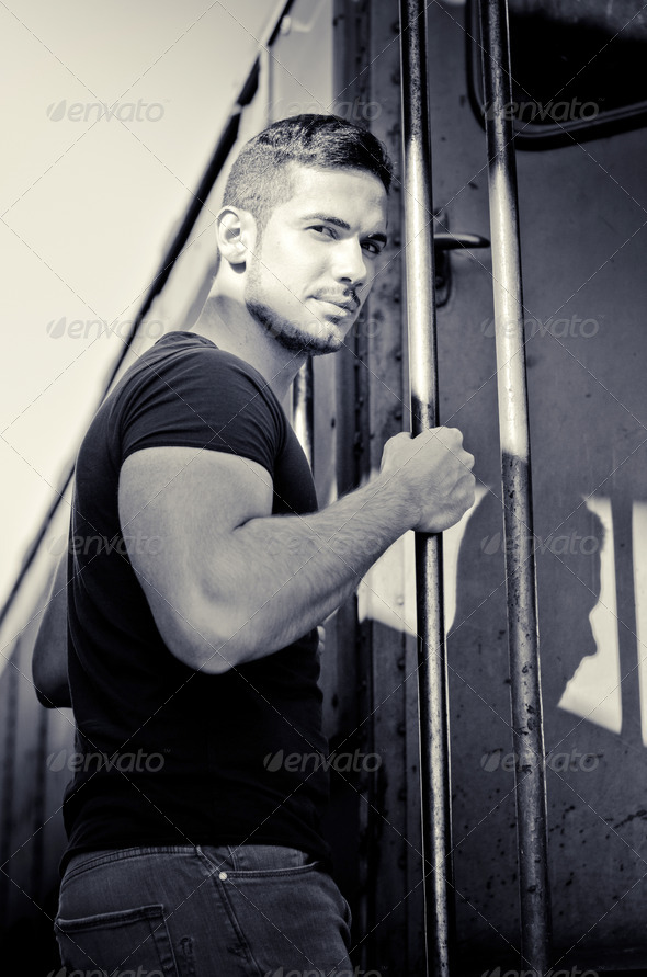 Handsome young man hanging from train handle