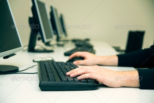 Young man typing on keyboard. Training room with computers