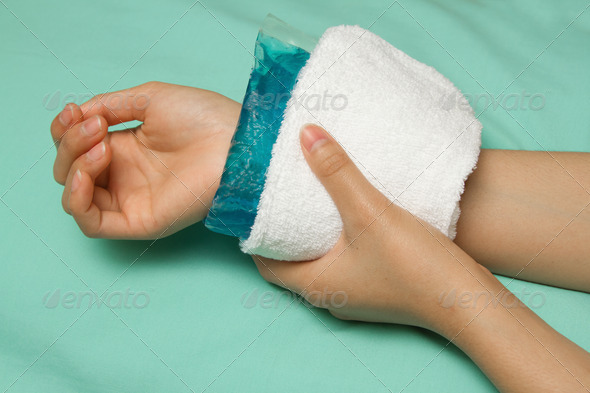 a woman applying cold pack on swollen hurting wrist after acci