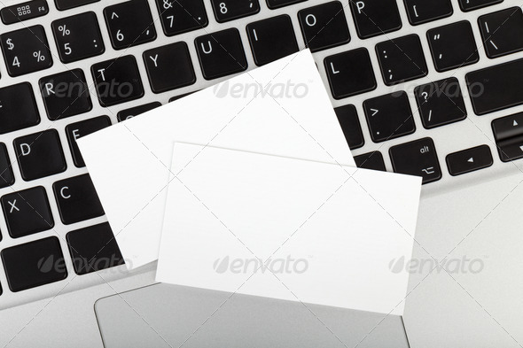 Blank business cards over laptop