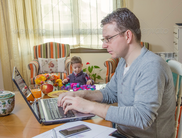 Father working in home office and son playing